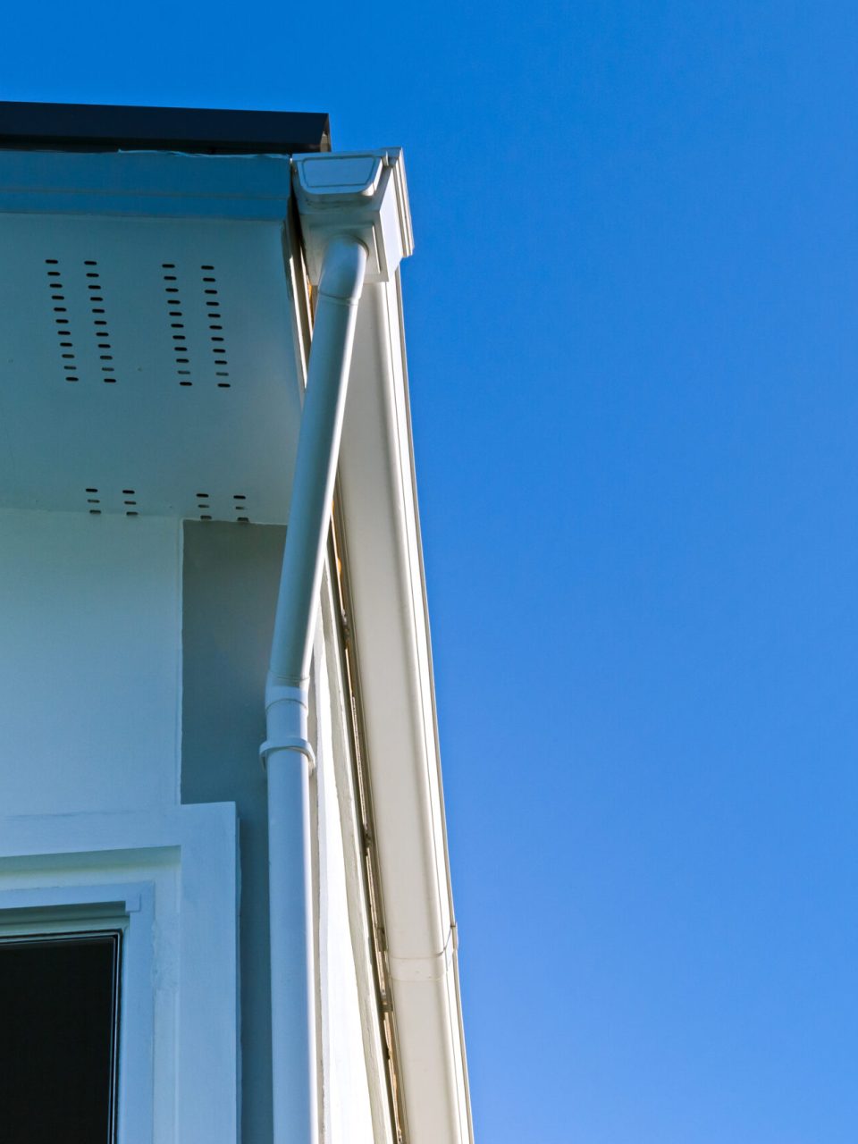 House roof with rain gutter of roof top house and large windows on blue sky background, New modern building